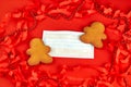 Gingerbread men on both sides of a surgical protective mask on a red background. Christmas during the covid-19 Royalty Free Stock Photo