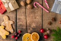 Gingerbread men, candy canes, dried oranges , pine branch, anis and christmas presents, ornaments and cranberries on wooden rustic Royalty Free Stock Photo