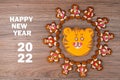 Gingerbread men with glaze put around the tiger-shaped orange gingerbread cookie on a wooden table. New year 2022 concept