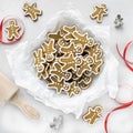 Gingerbread men on a white tablecloth next to a red ribbon and cookie cutters. Royalty Free Stock Photo