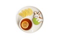 Gingerbread in the shape of a rabbit with an Easter egg, a cup of tea and lemon slices on a white plate Royalty Free Stock Photo