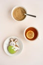 A gingerbread in the shape of a rabbit with an Easter egg, a cup of tea with lemon and a sugar bowl on a light table Royalty Free Stock Photo