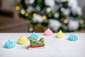 Gingerbread sleigh and meringue on the table in front of defocused lights of Christmas decorated fir tree. Holiday sweets. New Yea