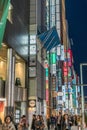 Billboards, neon signs and People enjoying nightlife in crowded Chuo dori street at Ginza luxurious shopping District by night