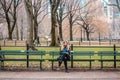 Gir sitting on a bench l in front of trees at the Central Park i Royalty Free Stock Photo