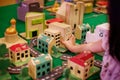 A girl adding a school wooden block to her modeled town