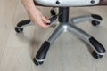 The girl adjusts the height of the new brown office chair.