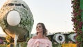 A girl admires in a city park on the background of an airplane of flowers. Royalty Free Stock Photo