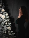 A girl admires a decorated New Year tree at home in the evening