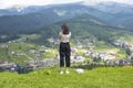 Girl admires the village in the valley. Mountains in the distance. Back view