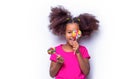 Girl afro, lollipops. Smile little african american girl eating lollipop, holding pink sweet colorful lollipop candy Royalty Free Stock Photo