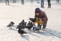 Girl age 6-8 years feeding pigeons at main square in old city Royalty Free Stock Photo