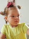 Girl aged 18 months with yellow top and hair up in ties