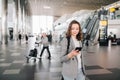 Girl at the airport, looking at her smartphone.