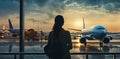 A girl at the airport window in the sunset looks at boarding for other flights. Generated by AI Royalty Free Stock Photo