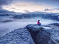 Girl alone sit on mountain summit likes ship in misty ocean Royalty Free Stock Photo