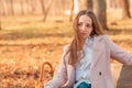 Girl alone sits with an umbrella in her hands on a bench in an autumn park