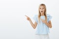 Girl amazed seeing magician trick. Portrait of fascinated admiring young blond daughter in trendy blue blouse, saying