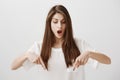 Girl is amazed standing on transparent floor. Portrait of overwhelmed attractive woman pointing down with index fingers