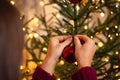 Girl anging a red ball on the christmas tree