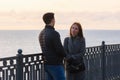 Girl anxiously looks at a guy near a railing in the background of the sea in cloudy weather