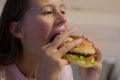 Girl with appetite eats delicious hamburger. child bites off large piece of sandwich