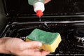 Girl applies detergent to a yellow washcloth close-up, cleaning the surface on the gas stove