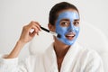 Girl applying facial blue clay mask Royalty Free Stock Photo