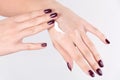 Girl applying hand cream on skin and girl has red wine nails polish gel Royalty Free Stock Photo