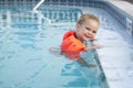 Girl with arm floats holding on to edge of pool