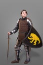 Girl in armor with a sword knight wuth shield over grey background Royalty Free Stock Photo