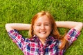 Girl with arms under her head lays on green grass