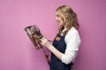 Girl artist holds brushes and a palette and smiles on a pink background, student of art school, profession of an artist