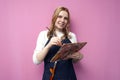 Girl artist holds brushes and a palette and smiles on a pink background, student of art school, profession of an artist