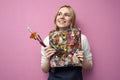 Girl artist holds brushes and a palette and smiles on a pink background, student of art school, profession of an artist