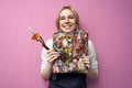 Girl artist holds brushes and a palette and smiles on a pink background, student of art school, profession of an artist