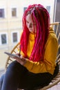 Girl artist, illustrator draws in notebook, makes sketches. Close-up of woman with long pink dreadlocks in informal setting, in Royalty Free Stock Photo