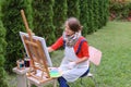 Girl artist paints picture and sits on chair at easel sides of t Royalty Free Stock Photo