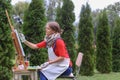 Girl artist paints picture and sits on chair at easel sides of t Royalty Free Stock Photo