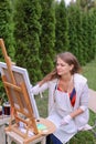 Girl artist paints picture and sits on chair at easel sides of t Royalty Free Stock Photo