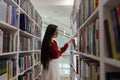 Girl asian student choose novel for project pick book from bookshelf in school or university library