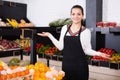 Girl assistant displaying fruits of grocery shop