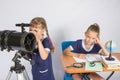 Girl astronomer looks at the sky through a telescope, the other girl is sitting at the table