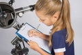 Girl astronomer writes on a sheet of paper of a starry sky with your telescope