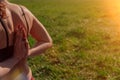 Girl athlete does a namaste pose from behind. Young female body hands closeup on a background of sunset Royalty Free Stock Photo