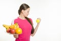 Girl athlete dumbbell raises his hand and other holding a fruit Royalty Free Stock Photo