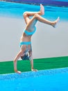 Girl athlete stands on his hands to jump into water