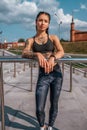 Girl athlete, summer city. Posing against the background of steps. In leggings sneakers. Woman with tattoos. Confident