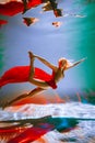 girl with an athletic figure, with red material and light underwear, in a ballet pose underwater Royalty Free Stock Photo