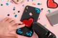 Girl attaching red heart patch onto black phone case
